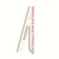 Gros plan detail d'un foulard en ruban de soie etroit avec motif chic et ton blanc casse. - Style 14