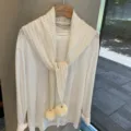 Detalle de bufanda chal de punto calado blanco con pompón y textura de lana prémium. - Blanco