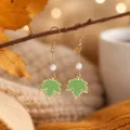 Close-up detail of autumn green maple leaf pendant earrings with white pearl and gold hook. - Green Maple Leaf Artificial Pearl Style (25080611-4)
