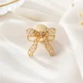 Close-up detail of a delicate gold-toned bow cufflink adorned with tiny pearls for elegant wear. - Hollow Bow Pearl (26080501-11)