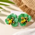 Vue rapprochée détaillée des boucles d'oreilles fleurs en émail vert avec des bords dorés. - Vert