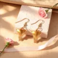 Eleganti orecchini a gancio dorati con ciondoli unici, decorati con garofani rosa e nastro grazioso. - Orecchini / oro lucido