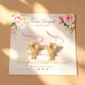 Eleganti orecchini pendenti con supporto floreale e ganci dorati per donna da indossare. - Orecchini con carta / Oro Opaco
