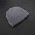 Close-up detail of a grey knitted beanie, showing fine ribbed texture and short dome shape. - One Size / Dark Gray