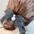 Detail shot of a black sheer mesh ribbon bow hair claw clip decorated with elegant pearls. - Black Double Layer Bow