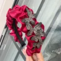 Nahaufnahme eines roten Satin Haarreifs mit Falten und funkelnden Strass Schmetterling Details. - Weinrot Schmetterling