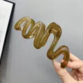 Detailed shot of a stylish translucent brown wavy hair claw clip, chic daily hair accessory. - Transparent Olive Green
