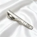 Gros plan d'une élégante pince à cravate en métal argenté avec gravure et strass brillants. - Argent Sculpté Strass