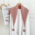 Pink knitted triangular scarf detail showing soft fabric texture and cute pom-pom design. - Pink