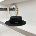 Detail view of a classic black straw boater hat with black pleated ribbon and gold metal accent. - M (56-58cm) / Black