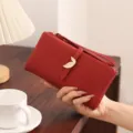 Red PU leather long wallet detail view showing elegant metal leaf buckle and practical wrist strap. - Red
