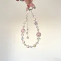 Detail shot of a sparkling crystal beaded phone charm with cute star tassels and pink beads. - Pink