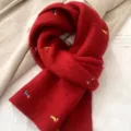 Red knitted scarf with cute dachshund embroidery, cozy winter accessory detail shot view. - Red