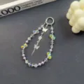Close-up detail of crystal phone charm with butterflies and purple pearls, exquisite decor. - Purple