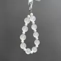 Detail view of the white translucent beaded phone charm and stylish bag pendant. - White