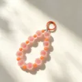 Dettaglio cinturino per telefono con perline colorate, perle sfumate e anello portachiavi. - Arancione