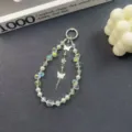 Detailed view of luxury crystal beaded phone charm with butterfly pendants and pearl accents. - Green