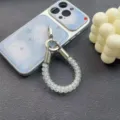 Close-up detail shot of transparent coiled phone lanyard strap featuring silver metal clasp. - White