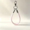 Detail shot of colorful TPU telephone cord wrist phone strap with durable metal clasp for secure hold. - Pink Musical Note