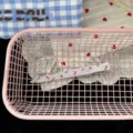 Close up view of the sweet strawberry printed long hair clip inside pink mesh basket detail. - Red Bow Long Hair Clip