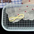 Detail shot of a cute yellow polka dot hair clip inside a blue mesh basket with lace fabric. - Beige Bow Hair Clip