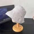 Vista detallada de sombrero de pescador japonés gris claro con costuras en soporte de madera. - Violeta Claro