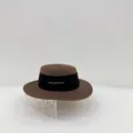 Vista detallada del sombrero de paja marrón con cinta negra y detalle de metal dorado. - M (56-58cm) / Café