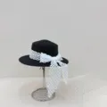Vista detallada de un elegante sombrero de paja negro con lazo a cuadros blancos. - M (56-58cm) / Negro