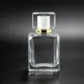 Detail view of the clear glass perfume bottle featuring a square cap and golden collar. - 30ml / White Flap