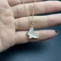 Close-up detail shot of the gold-tone butterfly pendant necklace with white mother-of-pearl. - Gold