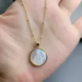 Close-up detail of the mother of pearl Mary pendant necklace, delicate gold chain design. - Virgin Mary