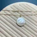 Detailed close-up view of a gold box chain necklace featuring a round white pearl pendant. - Round