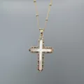 Gold cross necklace detail featuring a white shell inlay and colorful cubic zirconia pavé border. - Gold