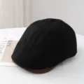 Close-up detail of the black newsboy flat cap featuring a contrast brown brim and texture. - M (56-58cm) / Black