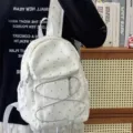 Detailed close-up view of the white polka dot backpack showcasing front pocket and elastic cords. - Moon Pendant / S / White