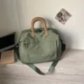 Borsa da viaggio in tela verde con ricamo fiocco, manici superiori e tracolla regolabile. - Verde