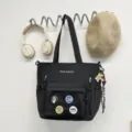 Sac cabas noir en toile avec plusieurs poches, une bandoulière et des jolis badges. - Sac Fourre-tout / Avec Pendentif / Noir