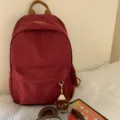 Casual red backpack variant with brown handle and cute plush keychain accessory for daily use. - Hat Elf Pendant / Burgundy