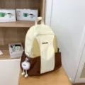 Color-block casual canvas backpack with front zipper pocket and cute plush pendant charm. - Brown with Long Leg Ball