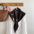 Gros plan détaillé du foulard triangulaire tricoté marron foncé avec broderie florale. - Café - Fleur Brodée / 140*33cm