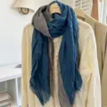 Detailed view of the blue and grey linen crinkled scarf draped on a light blouse hanger. - 180x68cm / Denim Blue Gray