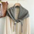 Detail shot of grey hollow knit triangular scarf, featuring delicate texture and elegant drape. - Gray
