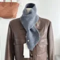 Primo piano dettagliato della sciarpa incrociata in maglia grigia su manichino con giacca in pelle. - Grigio