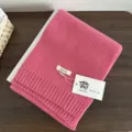 Detail view of a soft pink wool knit scarf with brand tag, perfect for winter warmth. - Baby Pink