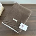 Detailed view of a cozy brown knitted wool scarf, showcasing soft texture and warm winter fabric. - Coffee