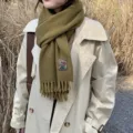 Olive green cashmere-feel winter scarf detail showing cozy texture and woven tag design. - Mustard Yellow