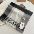 Detailed view of soft grey and white plaid wool scarf with cozy fringe and brand tag. - Black White Grey