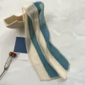 Close-up detail of pleated blue and white striped hair ribbon scarf, elegant styling prop. - Light Blue and Rice