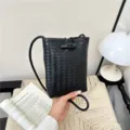 Black PU leather woven mini crossbody phone bag with toggle closure, stylish minimalist design. - Black