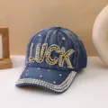 Primo piano del berretto da baseball in denim con lettere LUCK in strass e visiera di cristallo. - Stile Lettera LUCK / Blu jeans
